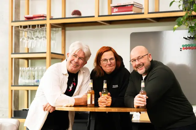 Drei Menschen lachen an einem Tisch
