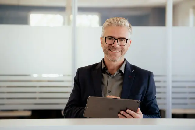 Mann mit Tablet lächelt im Büro